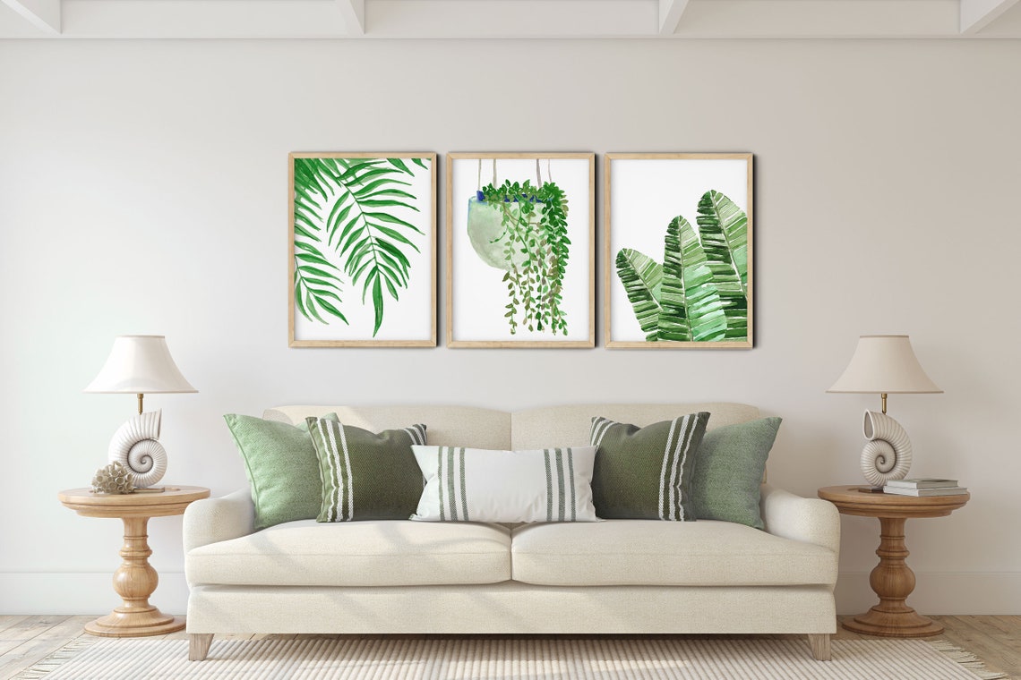Green leaf set of 3 hung above a cream sofa with striped cushions