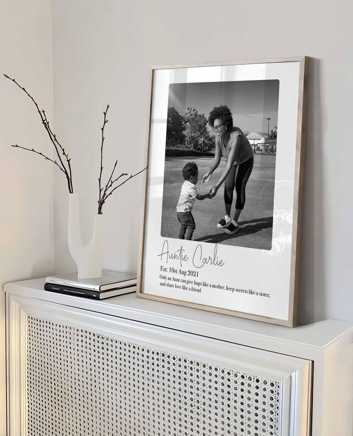 Framed Auntie Carlie photo print of an aunt playing with her nephew, leaning on a white cabinet