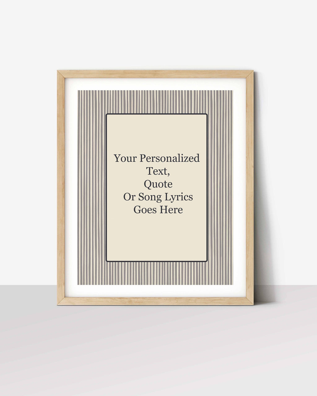 Striped personalized quote print in a white-matted oak frame, leaning against a wall