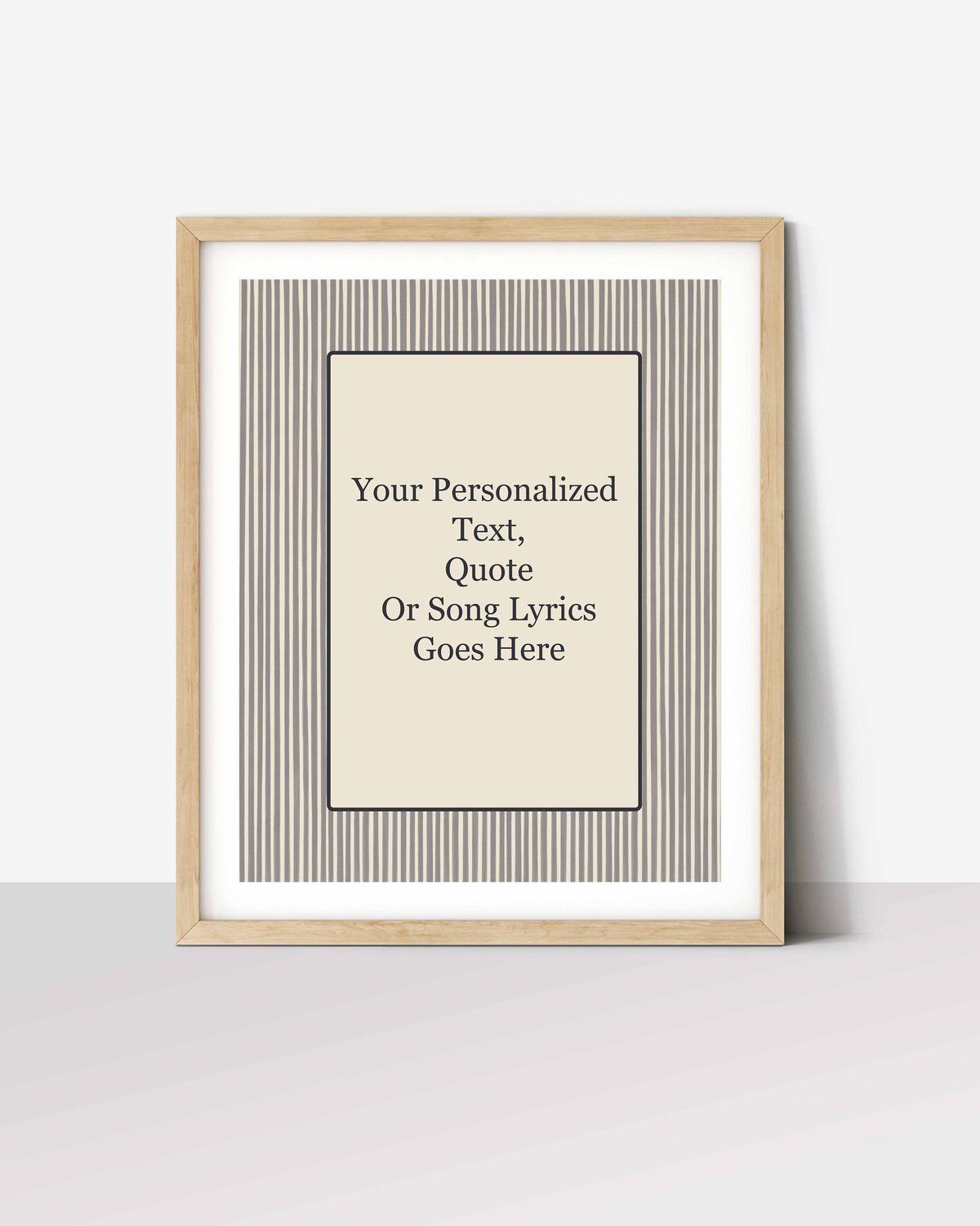 Striped personalized quote print in a white-matted oak frame, leaning against a wall